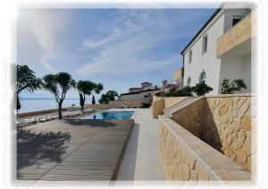 a house with a wooden walkway next to a swimming pool at Villa Ivanovic in Vir