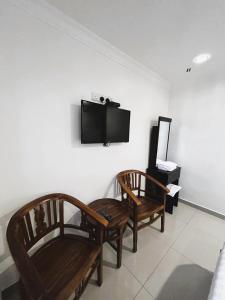 a living room with two chairs and a flat screen tv at Hotel Sagittario in Ipoh