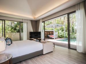 Avani Plus Khao Lak Resort في خاو لاك: غرفة نوم بسرير ابيض كبير ومسبح