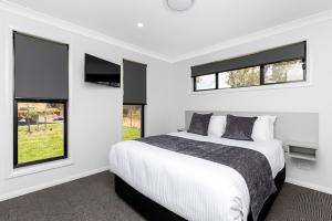 a white bedroom with a bed and two windows at CH Boutique Apartments The Ringers Road in Tamworth