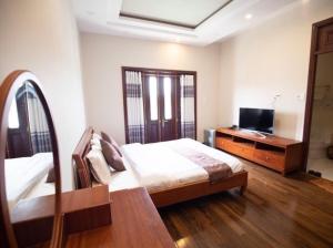 a bedroom with a bed and a dresser and a television at Villa Lan Rung Da Lat - Venuestay in Da Lat