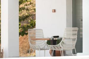 dwa białe krzesła i stół na ganku w obiekcie Villa Lino w mieście Skiros