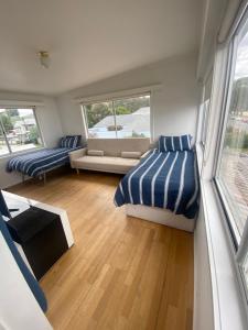 a bedroom with a bed and a couch and windows at The Ultimate Beach House in Kingston Beach