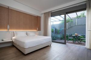 um quarto com uma cama branca e uma grande janela em Athens Hill Luxury Apartments em Atenas