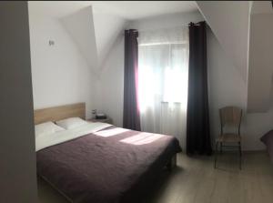 - une chambre avec un lit, une chaise et une fenêtre dans l'établissement Casa Elysium, à Vălenii de Munte