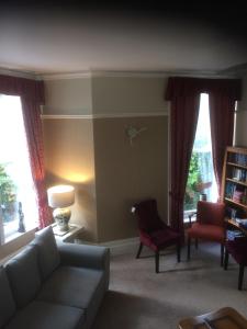 uma sala de estar com um sofá, cadeiras e janelas em The Brandize Guest House em Torquay