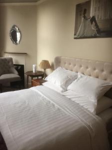a bedroom with a large white bed and a chair at The Brandize Guest House in Torquay