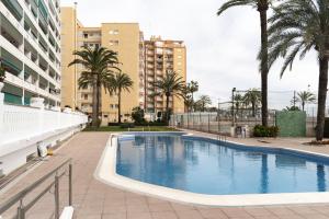a swimming pool with palm trees and buildings at Lider, 44-E (Planta Baja) in Cullera +11 photos