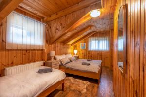 two beds in a room with wooden walls and windows at Holiday home Palo santo in Gospić