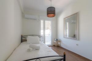 een witte slaapkamer met een bed en een spiegel bij Elegant Apartment With Acropolis View in Athene