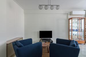 een woonkamer met twee blauwe stoelen en een televisie bij Elegant Apartment With Acropolis View in Athene