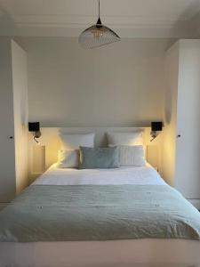 1 dormitorio con 1 cama blanca grande con almohadas azules en Superbe T2 climatisé au centre + parking, en Cannes