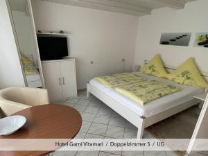 a small bedroom with a bed and a table at Hotel Garni Vitamari in Wasserburg