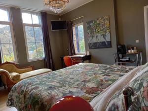 a bedroom with a bed and two windows and a chandelier at B&B Windsor - Guesthouse in Waulsort