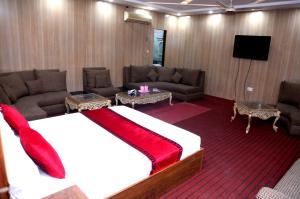 a room with a bed and couches and a television at Sapphire Inn Motel Lahore in Lahore