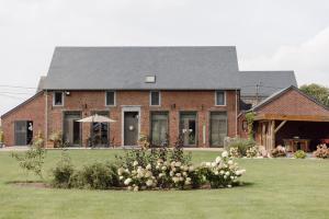 a large brick house with a yard with flowers at Le Relais De La Motte in Soignies