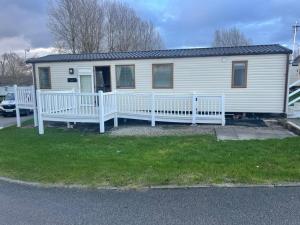a white mobile home with a porch and fence at Luxury 6 Berth Caravan, Marton Mere in Blackpool