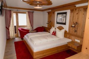 a bedroom with a white bed with a red rug at Gasthof zum Guten Tropfen in Partenen