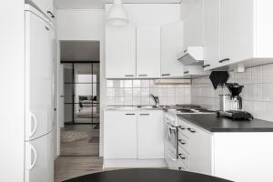 a kitchen with white cabinets and a black counter top at Fresh 2BR-apartment with FREE parking in Pori