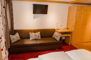 a living room with a couch and a table and a television at Gasthof zum Guten Tropfen in Partenen