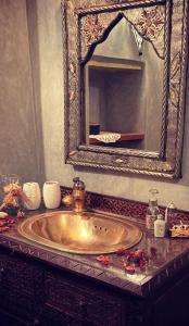 baño con lavabo de oro y espejo en Riad Felloussia, en Meknès