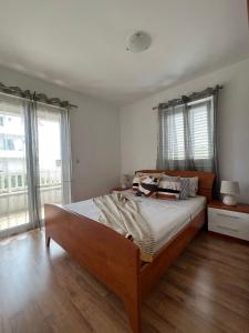een slaapkamer met een groot bed, houten vloeren en ramen bij Apartmani Bakovic in Hvar