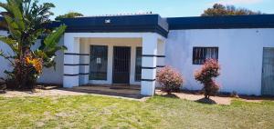 una pequeña casa blanca con una puerta y algunas plantas en Sweet Home39 Guest House Summerstrand en Port Elizabeth