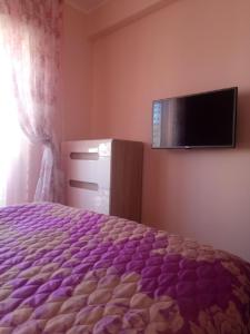 Schlafzimmer mit einem lila Bett und einem Flachbild-TV in der Unterkunft Apartman in Budva Podkošljun in Budva