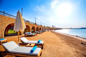 a beach with lounge chairs and an umbrella at Zen Resort Sahl Hasheesh by TBH Hotels in Hurghada