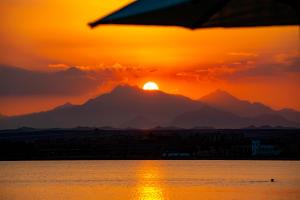 a sunset with the sun setting behind a mountain at Zen Resort Sahl Hasheesh by TBH Hotels in Hurghada
