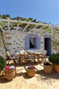 Good Life Greece Eco Villas في Posidhonía: فناء مع طاولة وكراسي والنباتات الفخارية