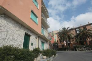 un bâtiment sur le côté d'une rue bordée de palmiers dans l'établissement DIAMANTE BLU Cod.Citra 011019-LT-0241, à Monterosso al Mare