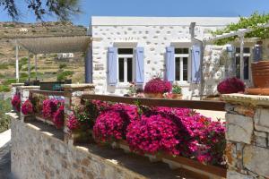 Good Life Greece Eco Villas في Posidhonía: منزل أبيض مع الزهور الأرجوانية على الحائط