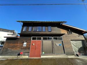 ein Haus mit einer roten Tür und Fenstern in der Unterkunft GuestHouse Shirakawa-Go INN in Shirakawa-gō