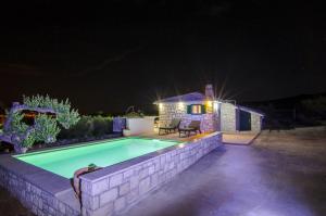 een zwembad voor een huis 's nachts bij Holiday Home Bliss in Splitska
