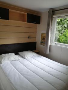 Bett in einem Schlafzimmer mit Fenster in der Unterkunft Camping La Loire Fleurie in Le Perrier
