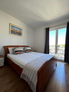 een slaapkamer met een groot bed en een groot raam bij Apartmani Bakovic in Hvar