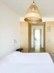 a bedroom with a white bed and a chandelier at Il fenicottero, Marzamemi in Marzamemi