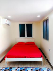 een rood bed in een witte kamer met ramen bij PS Din Kontenastay in Kota Bharu