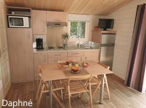 kuchnia z drewnianym stołem i krzesłami w kuchni w obiekcie Camping La Loire Fleurie w mieście Le Perrier
