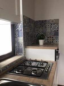 een kookplaat in een keuken met blauwe en witte tegels bij L'Ulivo in Villa Greco in Tindari