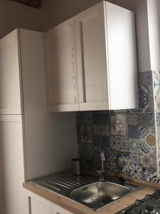 una cocina con armarios blancos y fregadero en L'Ulivo in Villa Greco, en Tindari