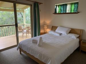 een slaapkamer met een bed met witte lakens en een balkon bij Nature Lovers Dream in Dawesville in Dawesville