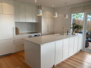 a kitchen with white cabinets and a kitchen island at Fern Ocean Views Middle of Town WiFi and Pet Friendly in Lorne