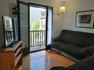 a living room with a couch and a television and a balcony at Apartamento con jardín y luminoso Besiberri 6 in Pla de l'Ermita