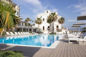 a swimming pool in front of a white building at Hotel & Resort Tre Fontane Luxury in Portici