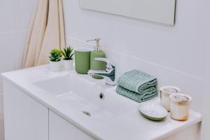 lavamanos blanco con toallas verdes y grifo en Faro: Casa Trevo com terraço BBQ, en Faro