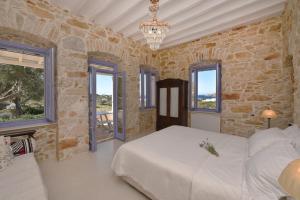PosidhoníaにあるGood Life Greece Eco Villasのベッドと石の壁のある寝室