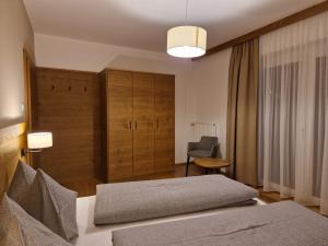 a bedroom with a bed and a chair in a room at Appartements Krautgasser in San Candido