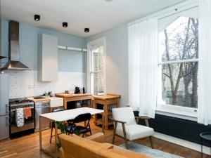 cocina con paredes azules, mesa y sillas en Pass the Keys Modern Condo in Brixton, en Londres